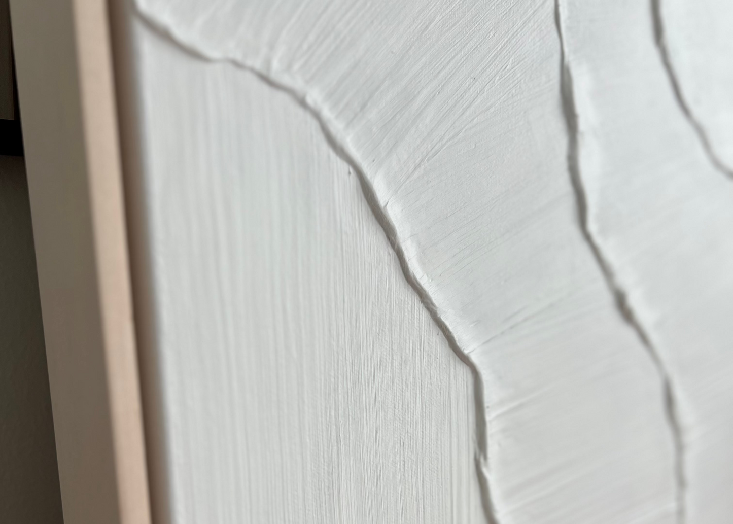 Close-up of a textured white wall panel with a wooden frame.