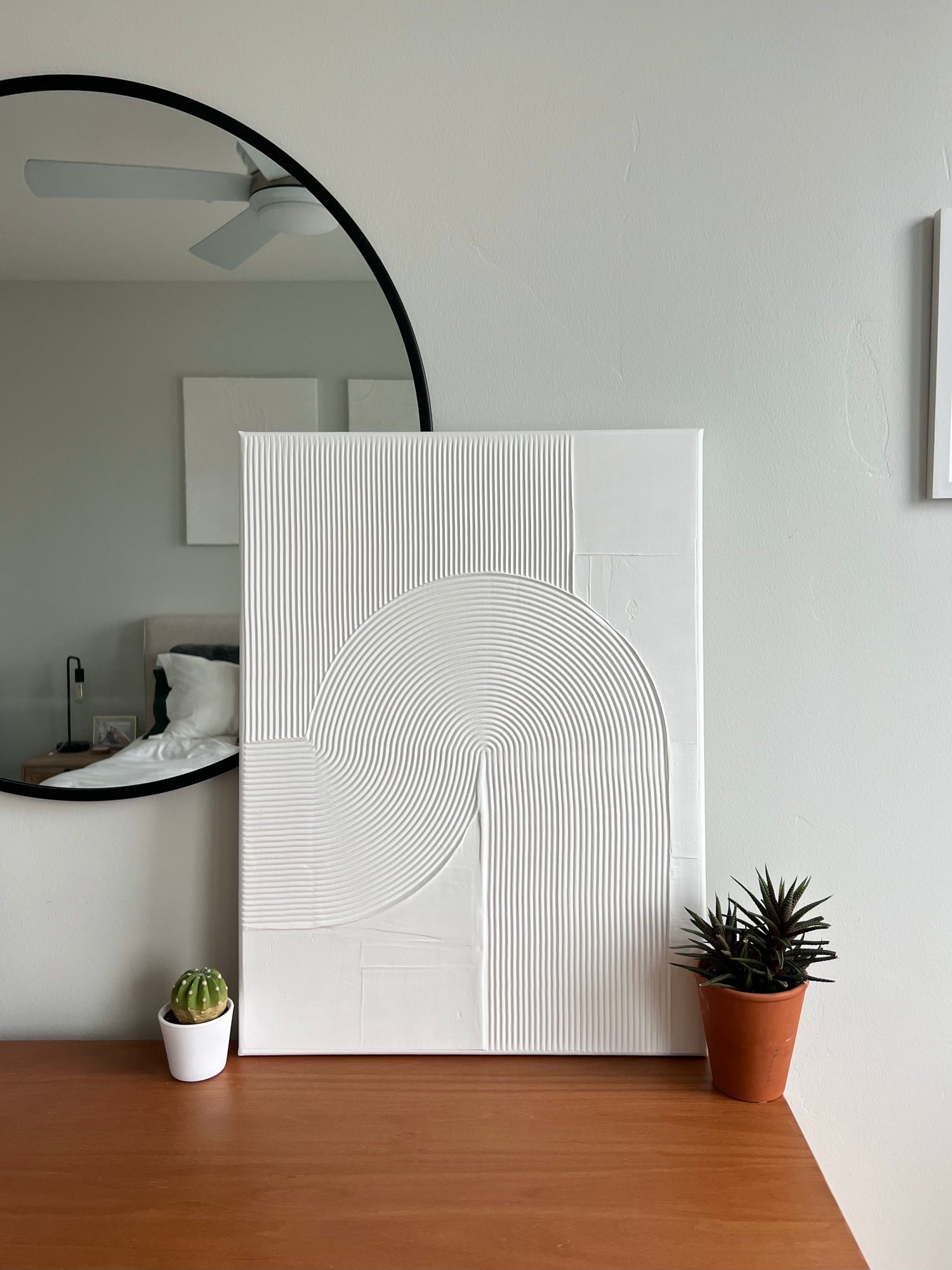 18x24 inch canvas with a white textured art design. Artwork is on top of a wood dresser with succulents next to the artwork.