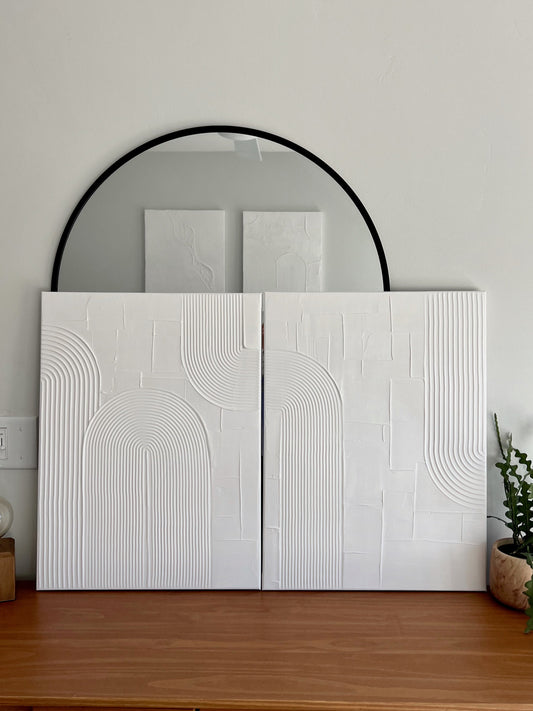 White textured wall panels with geometric patterns on a wooden surface against a light gray wall.