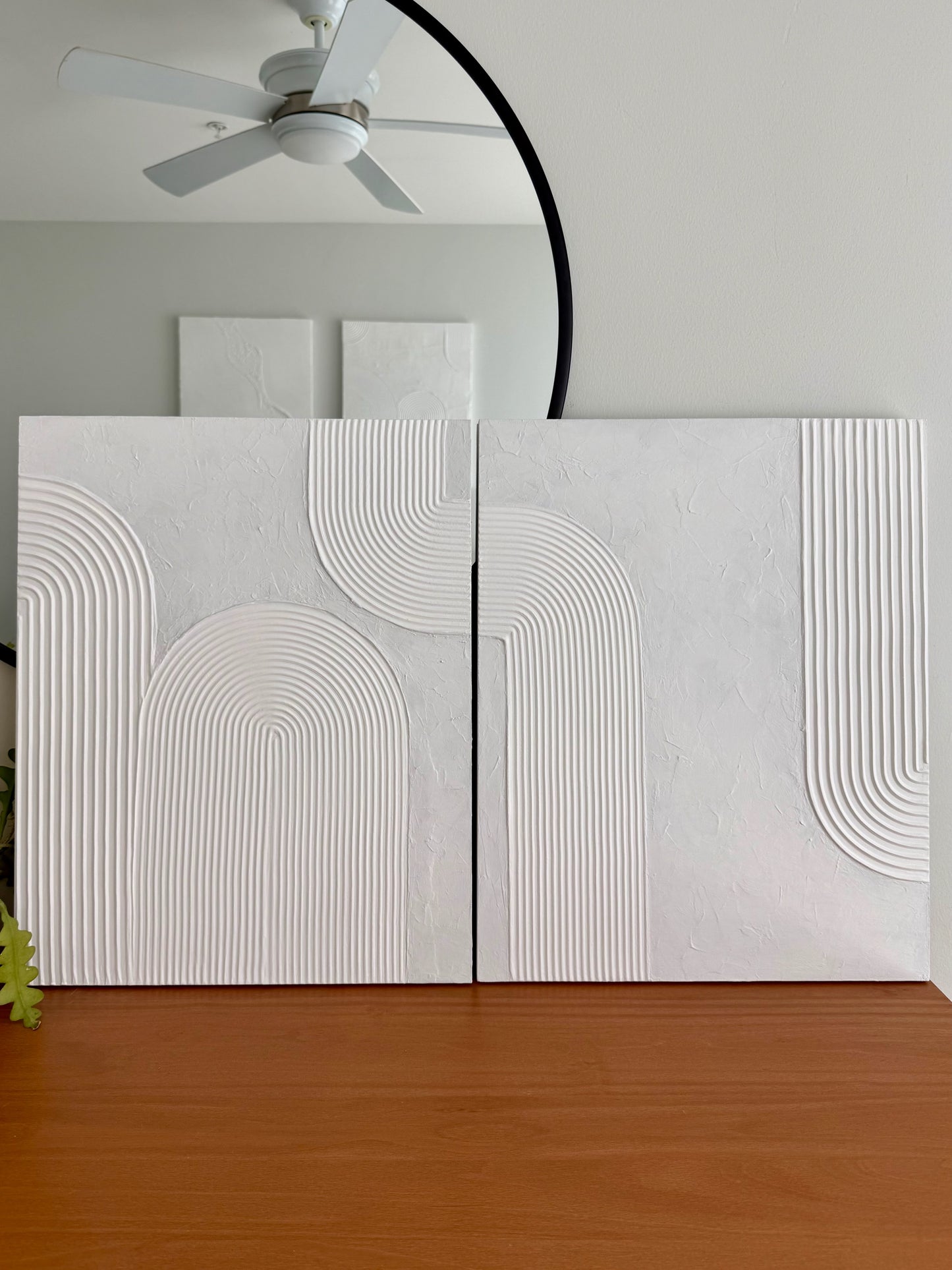 White textured wall panels with geometric patterns in a room with a ceiling fan and wooden floor.