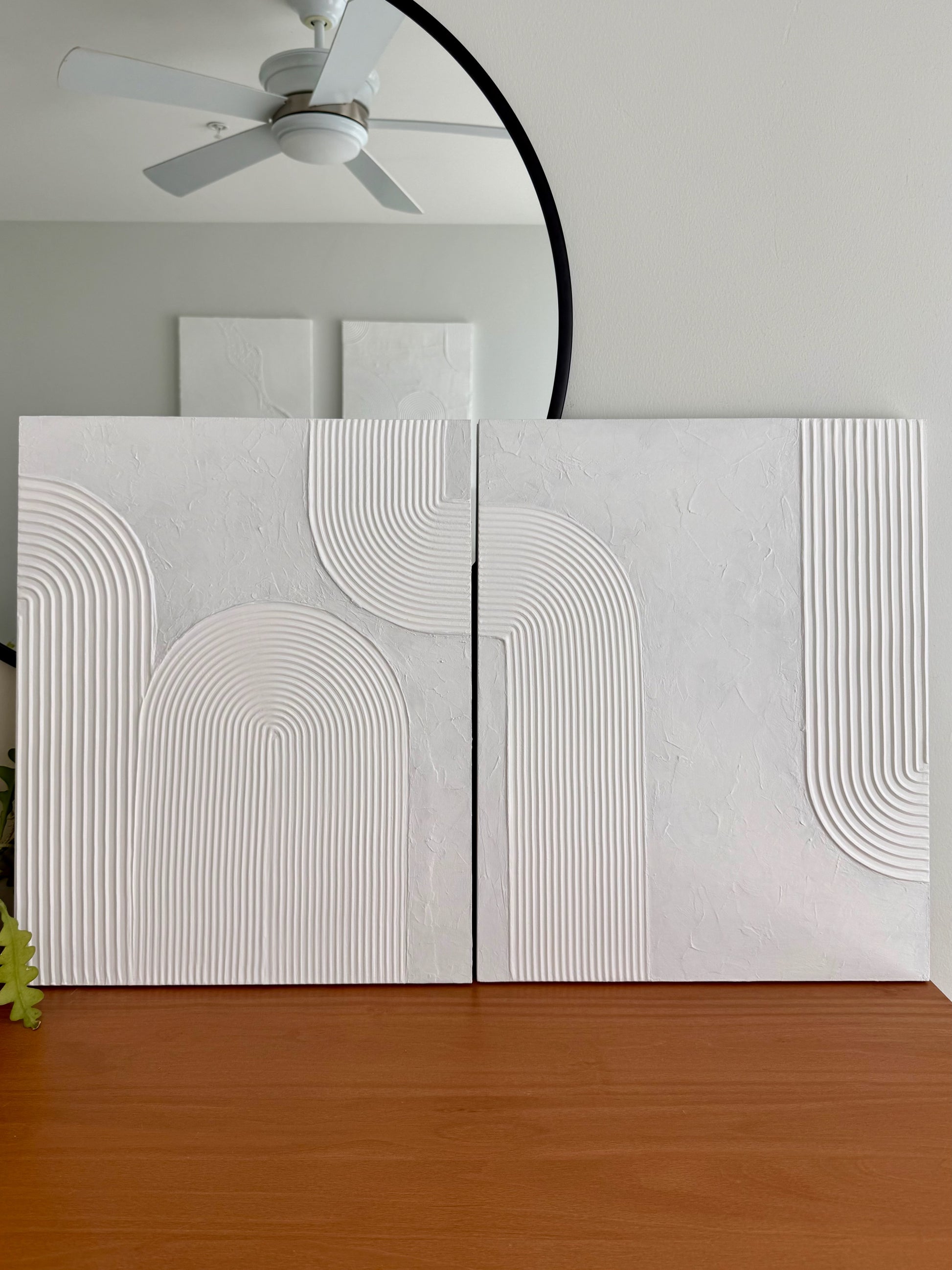 White textured wall panels with geometric patterns in a room with a ceiling fan and wooden floor.