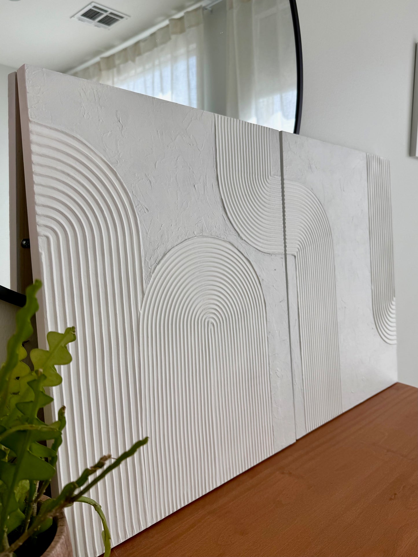 Textured wall panels with geometric pattern in a room with a plant and window.
