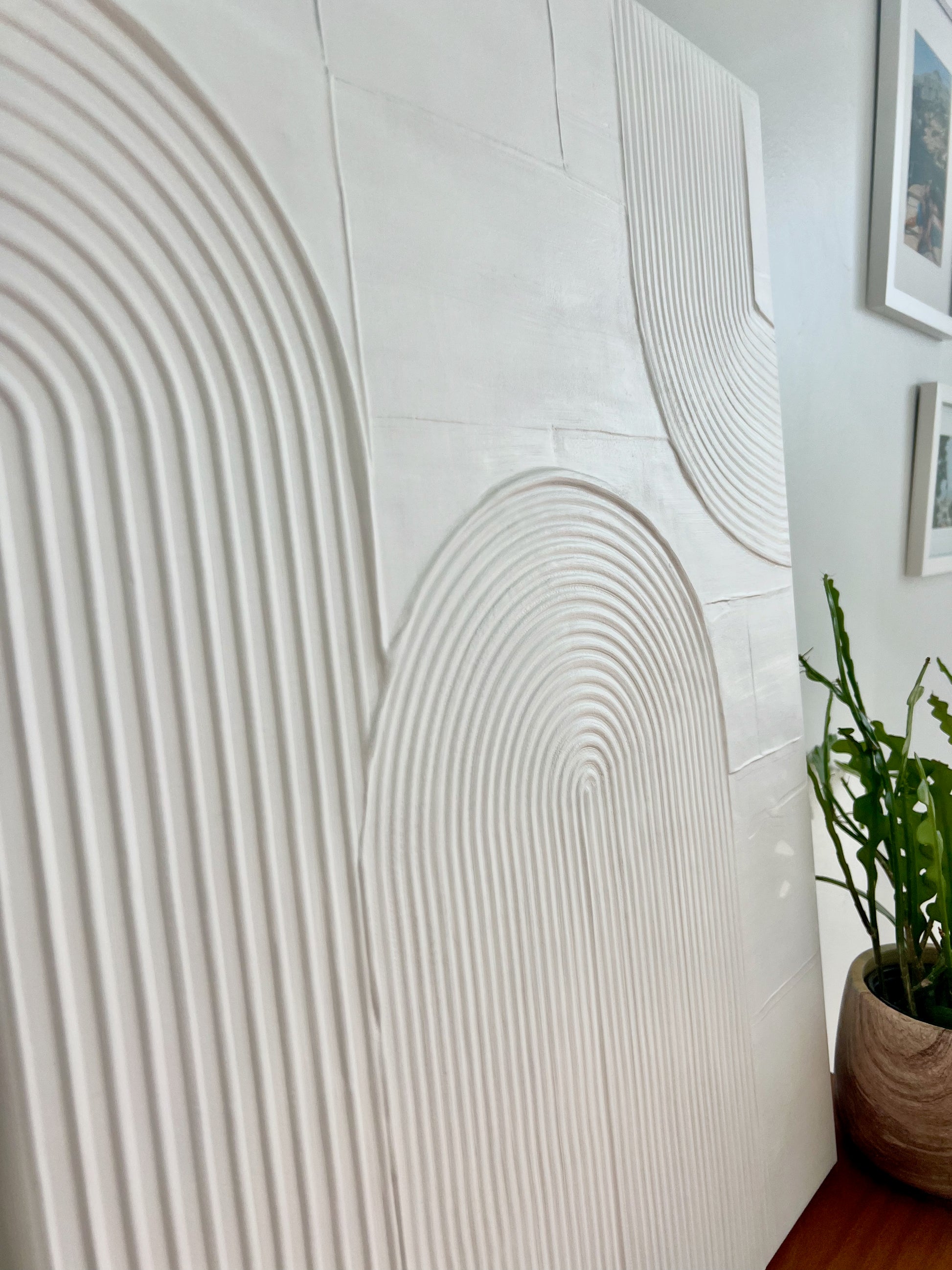 Textured wall panel with a plant on a wooden floor