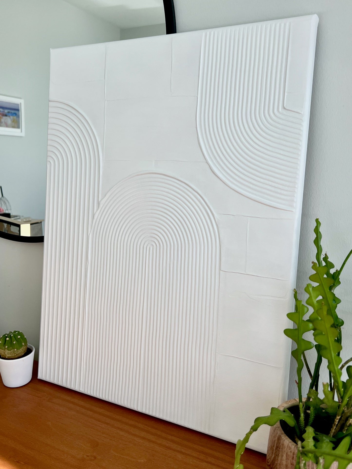 White textured wall panel in a room with plants and a mirror.