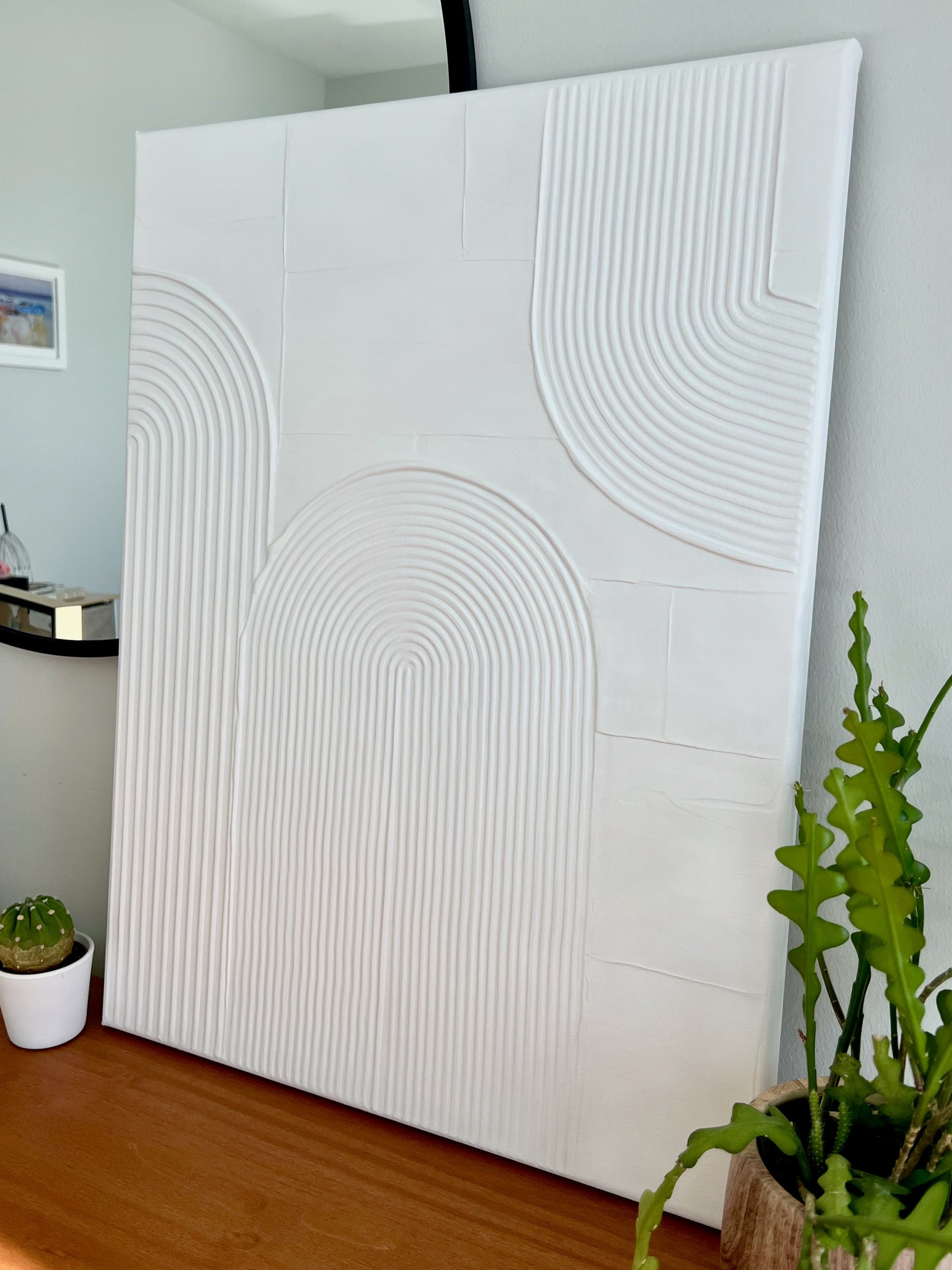 White textured wall panel in a room with plants and a mirror.