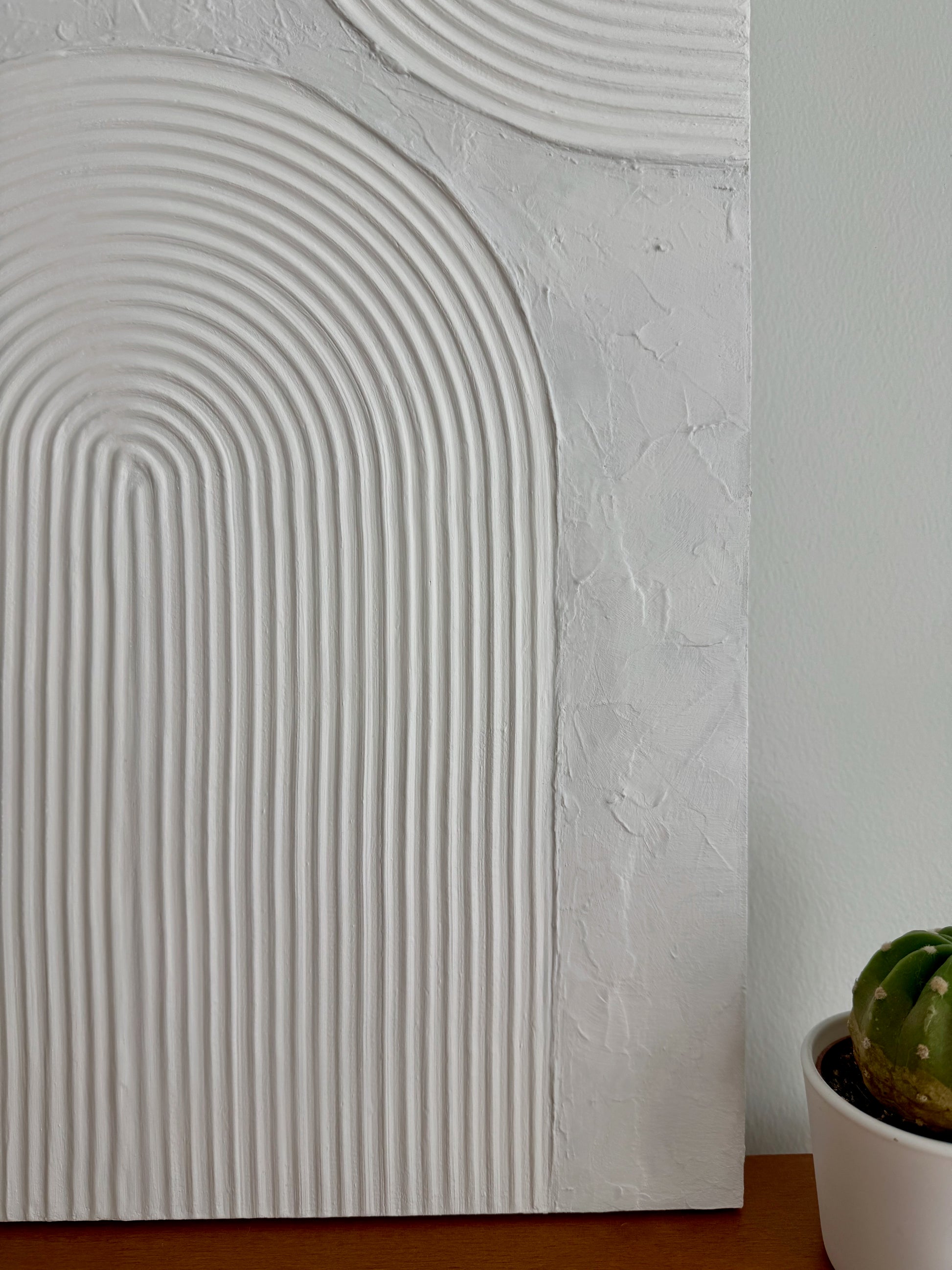 Textured wall panel with geometric pattern next to a potted plant
