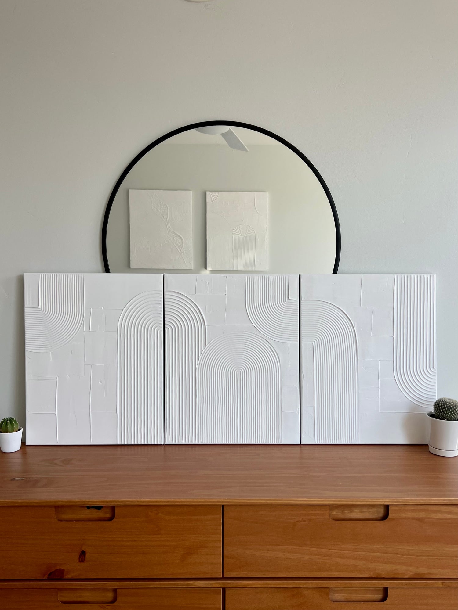 set of 3, 16x24 inch canvases with a connecting white textured art design, sitting on top of a wood dresser.