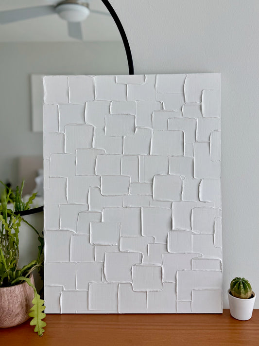White textured wall panel in a room with plants and a ceiling fan.