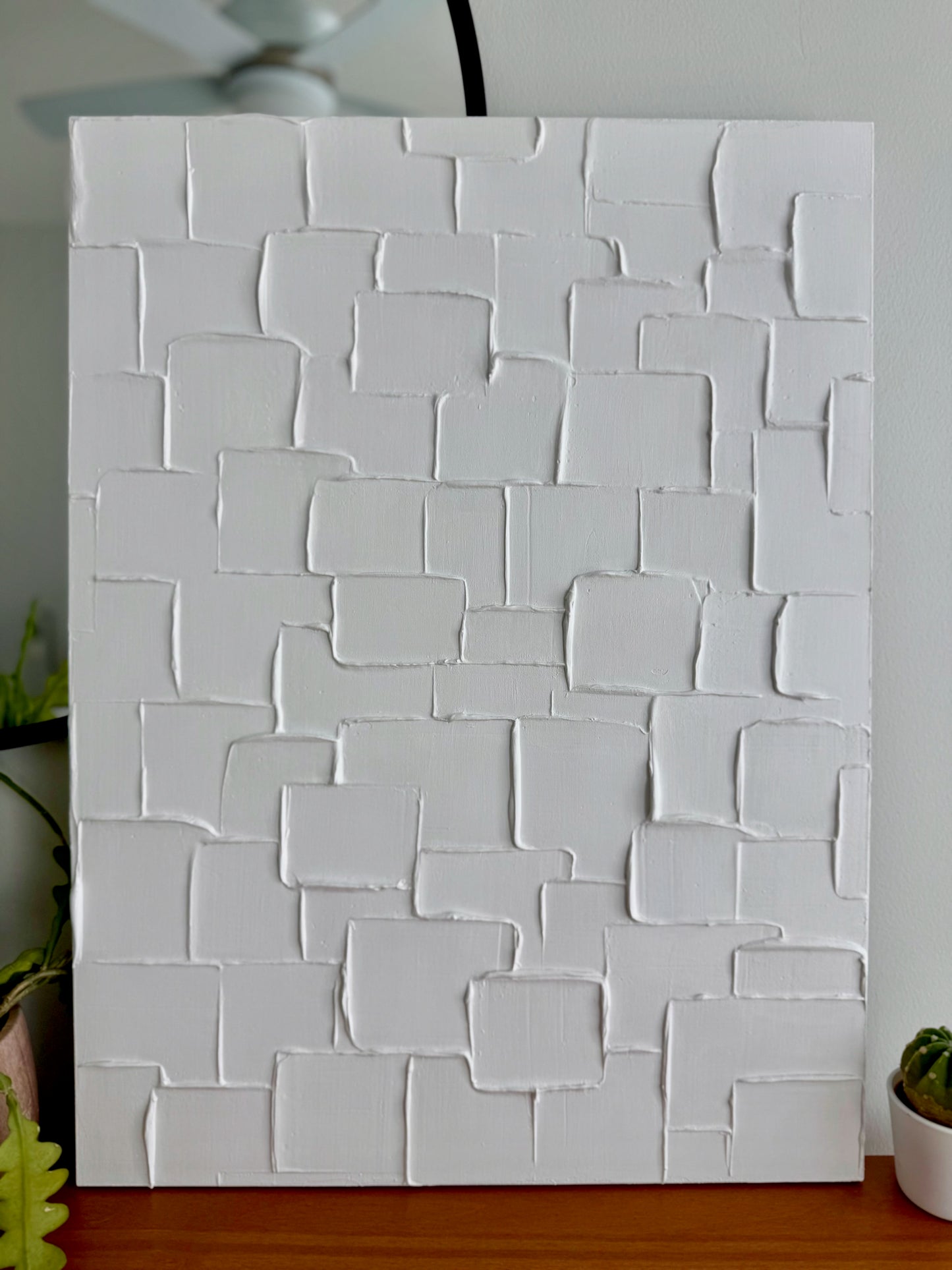 White textured wall panel on a wooden surface with a blurred background