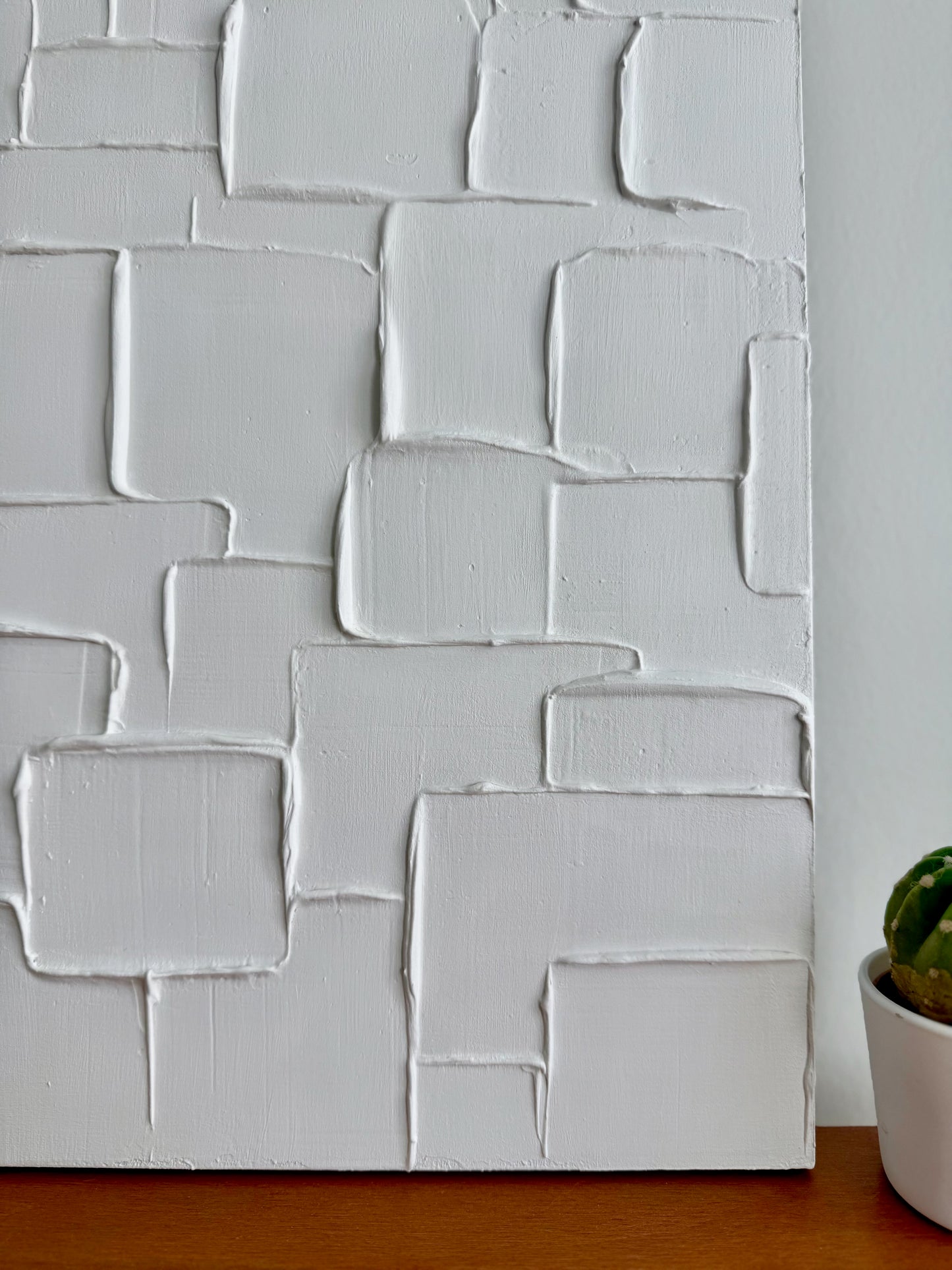 Textured white wall panel with geometric pattern on a wooden surface
