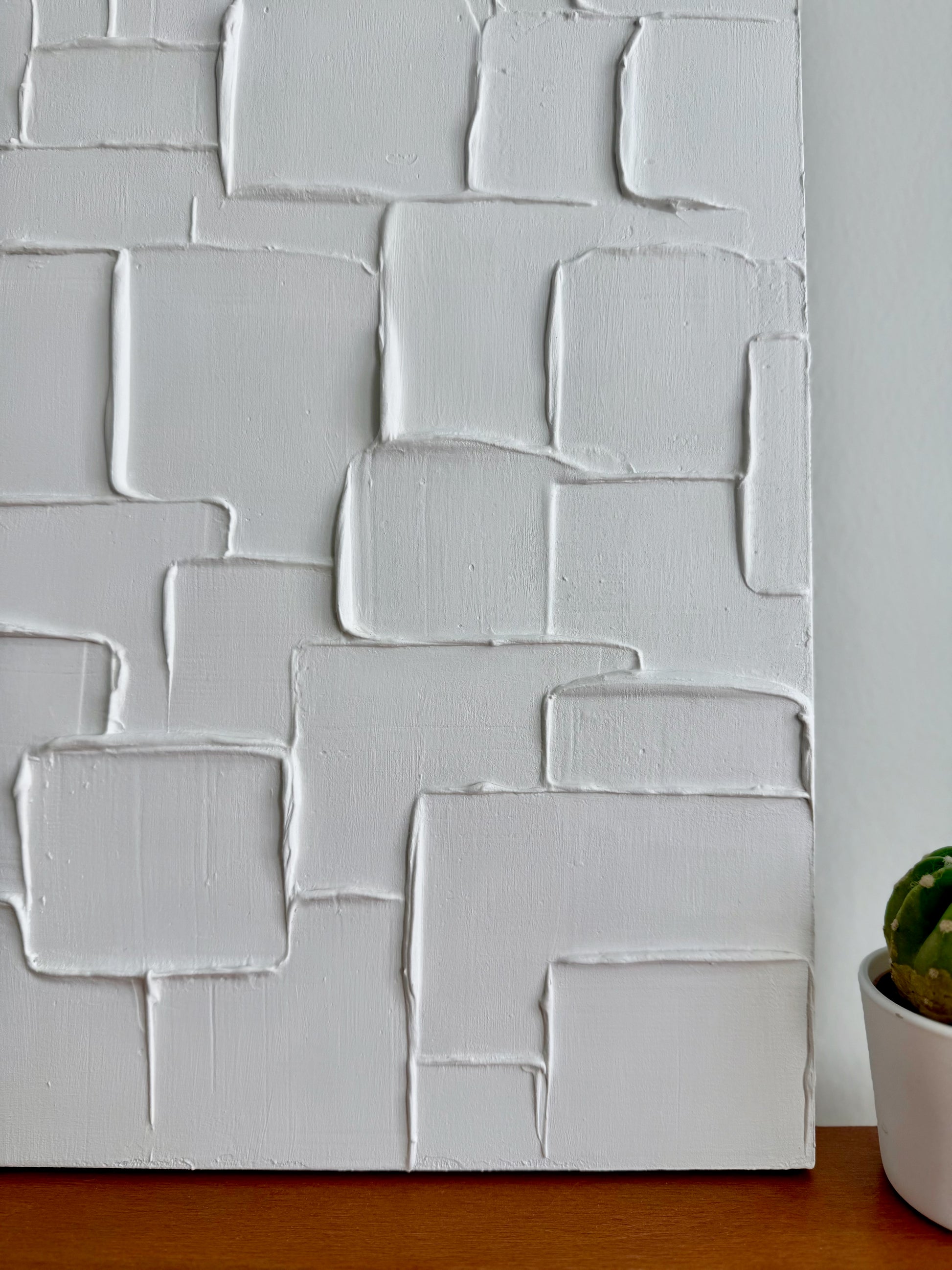Textured white wall panel with geometric pattern on a wooden surface
