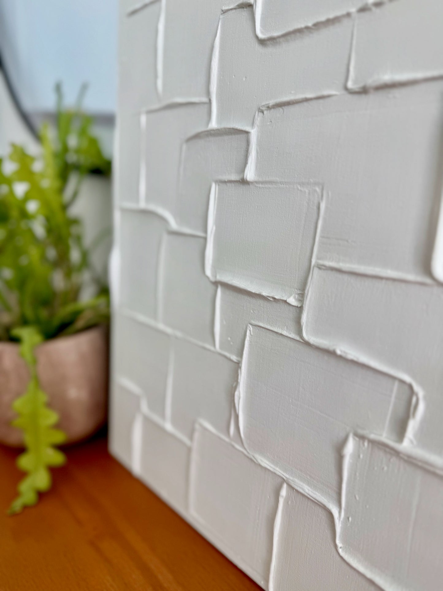 White textured wall panel with a plant in the background