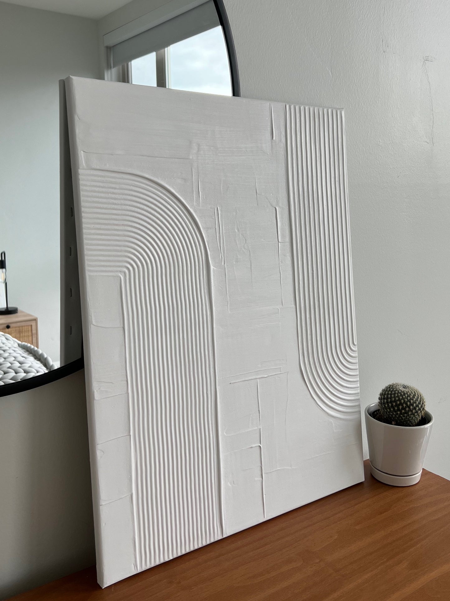White textured wall panel on a wooden surface with a cactus plant in the background